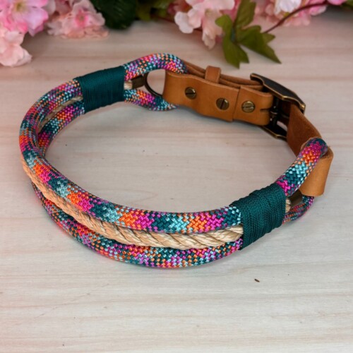 Hundehalsband aus Tau / PPM in pastell-Regenbogenfarben und Lederverschluss auf einer Holzplatte mit Dekoblumen